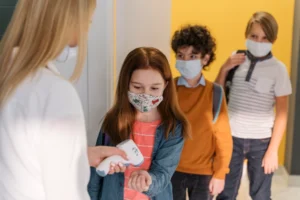 Kinder Fiebermessern in der schule während der Pandemie