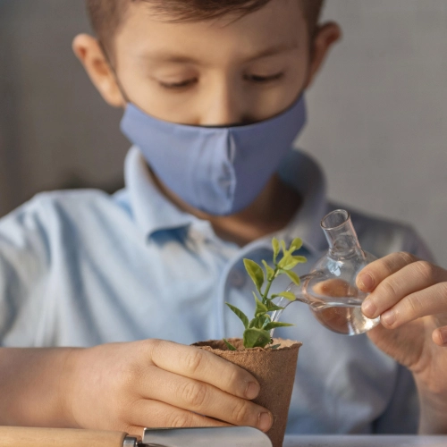 Ein Junge der Erprobungsstufe gießt eine Pflanze in Labor-Setiting