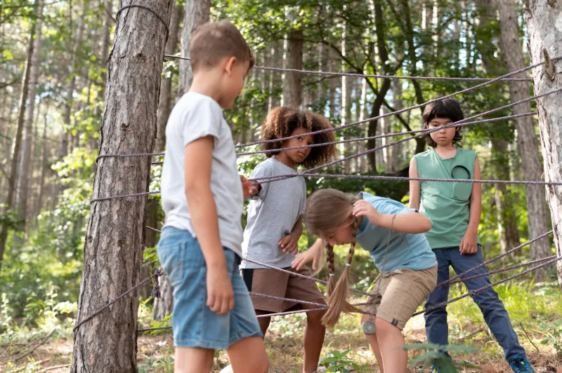 4 Kinder einer 5 . Klasse bei einer Kooperativen Problemlöse-Challenge im Wald.